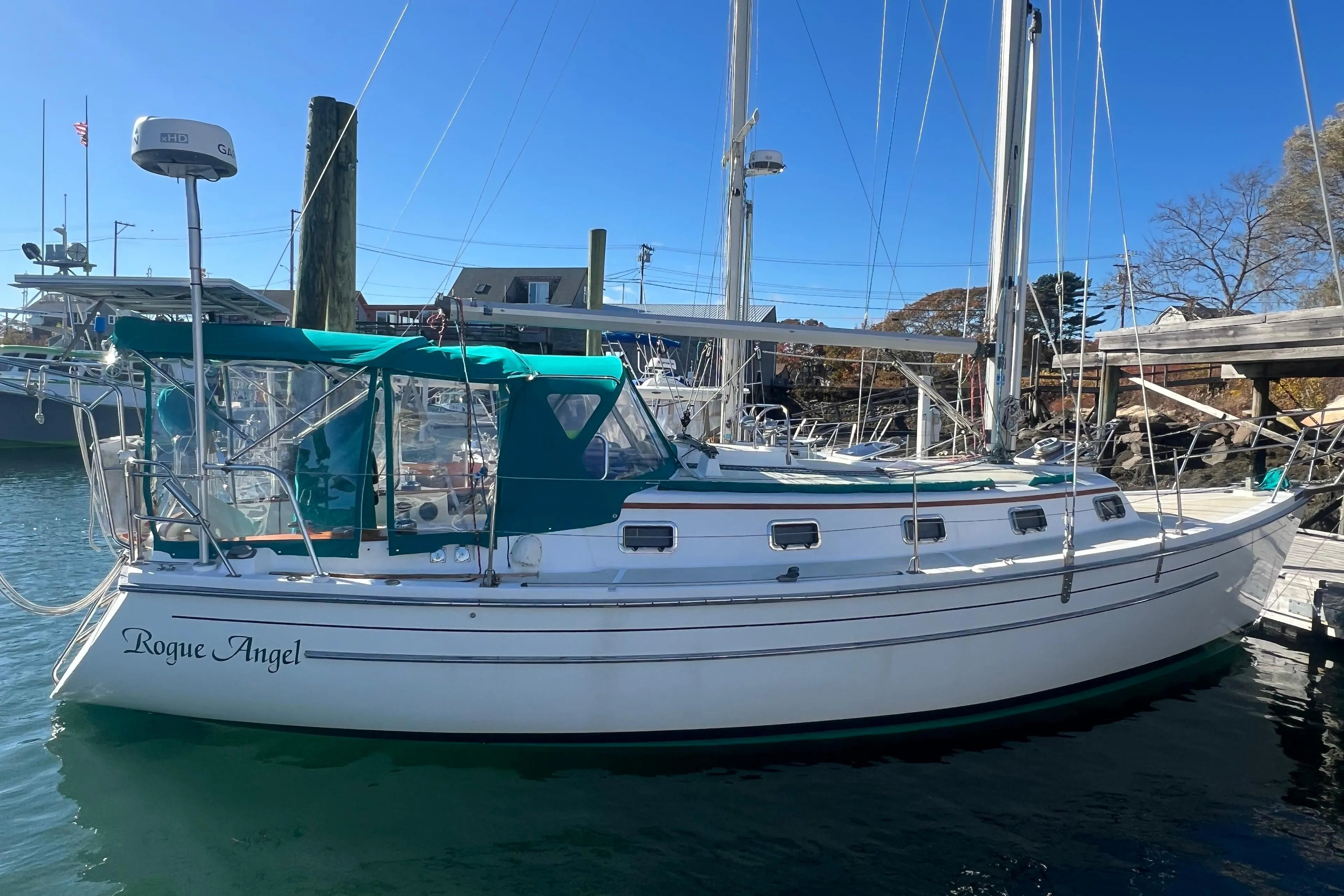 1993 Compac Sloop sailboat "Rogue Angel" docked in a marina under clear blue skies.