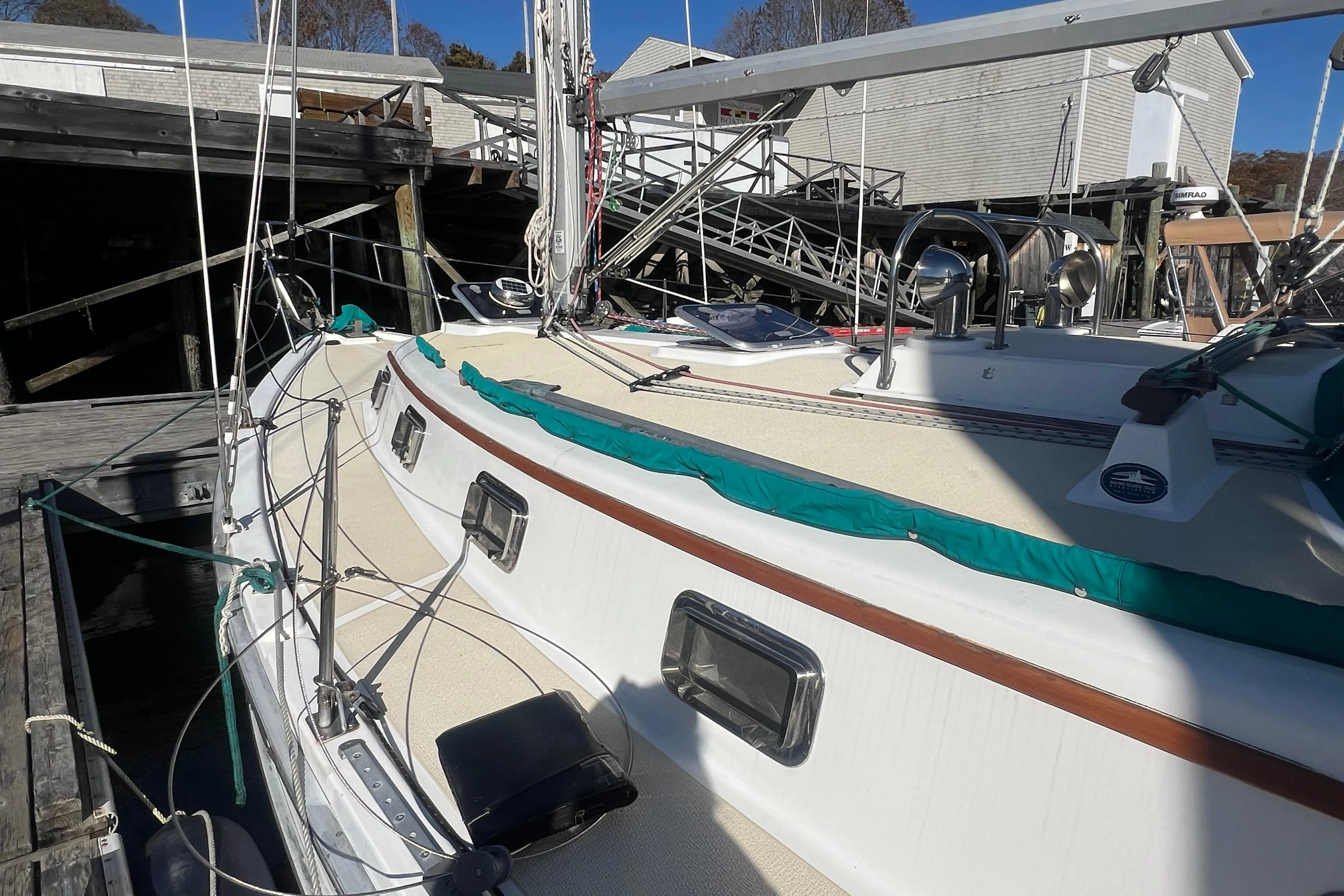 1993 Compac Sloop sailboat docked, featuring a clean deck and vibrant green trim.