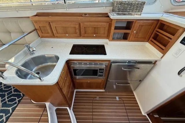 Someday Soon Yacht Photos Pics 2015 Back Cove 37 yacht kitchen with wooden cabinets, sink, stove, and microwave.