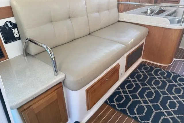 Someday Soon Yacht Photos Pics 2015 Back Cove 37 interior with beige seating, wooden cabinetry, and geometric rug.