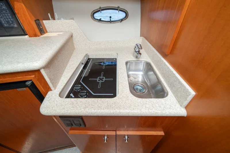 Wave Length Yacht Photos Pics Compact kitchen area in a 2001 Tiara Yachts 3500 Open, featuring a stove and sink.