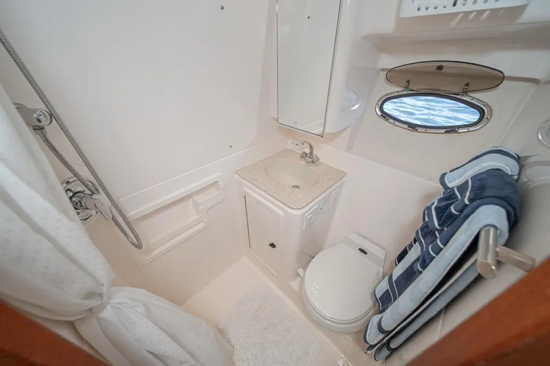 Wave Length Yacht Photos Pics Compact bathroom in 2001 Tiara Yachts 3500 Open, featuring shower, sink, and porthole window.