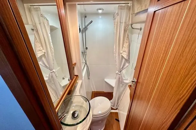 Topcat Yacht Photos Pics Compact bathroom in 2022 Aspen C120 with shower, glass sink, and wooden accents.