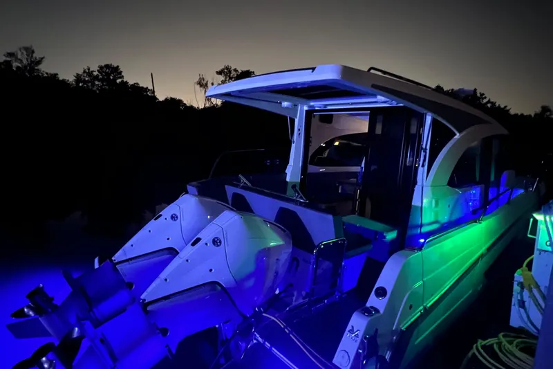 Seawalkin Yacht Photos Pics 2022 Beneteau Antares 11 boat illuminated with blue and green lights at night.