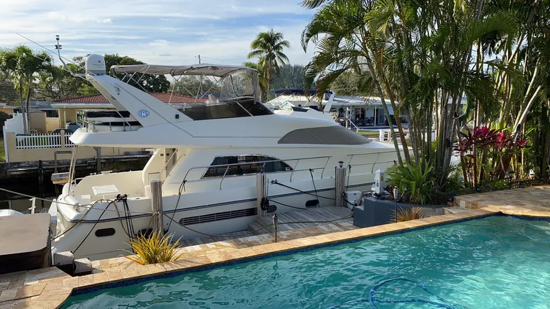  Yacht Photos Pics 1995 Neptunus 58 Flybridge yacht docked near a pool, surrounded by tropical plants.