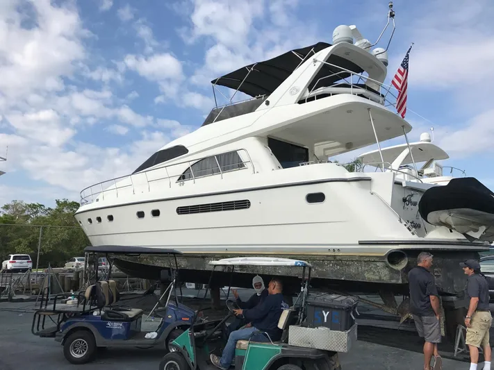  Yacht Photos Pics 1995 Neptunus 58 Flybridge yacht on land with people and golf carts nearby.