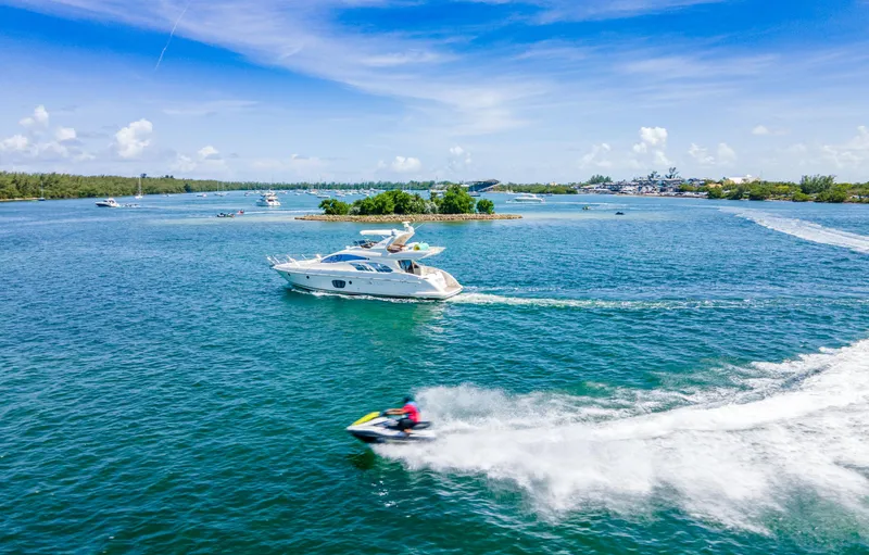  Yacht Photos Pics 2005 Azimut 55E yacht cruising on a sunny day with a jet ski nearby.