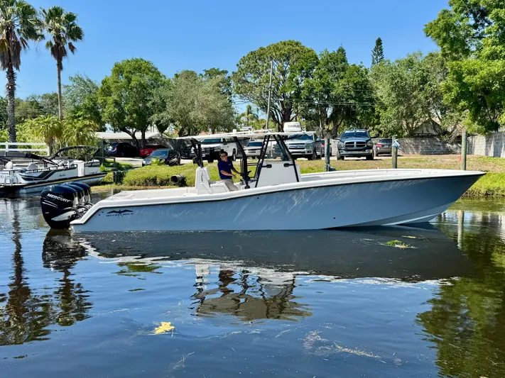  Yacht Photos Pics 2009 Invincible 36 Open Fisherman boat on calm water, surrounded by trees and parked vehicles.