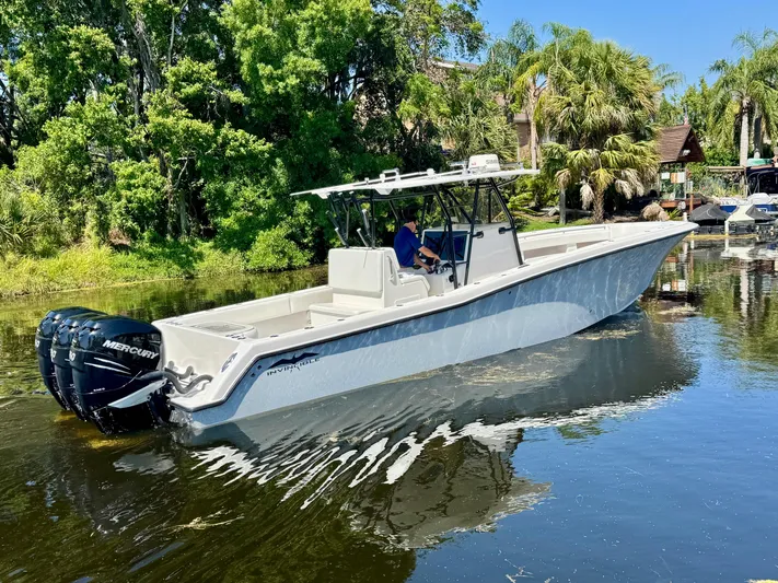  Yacht Photos Pics 2009 Invincible 36 Open Fisherman boat on calm water, surrounded by lush greenery.