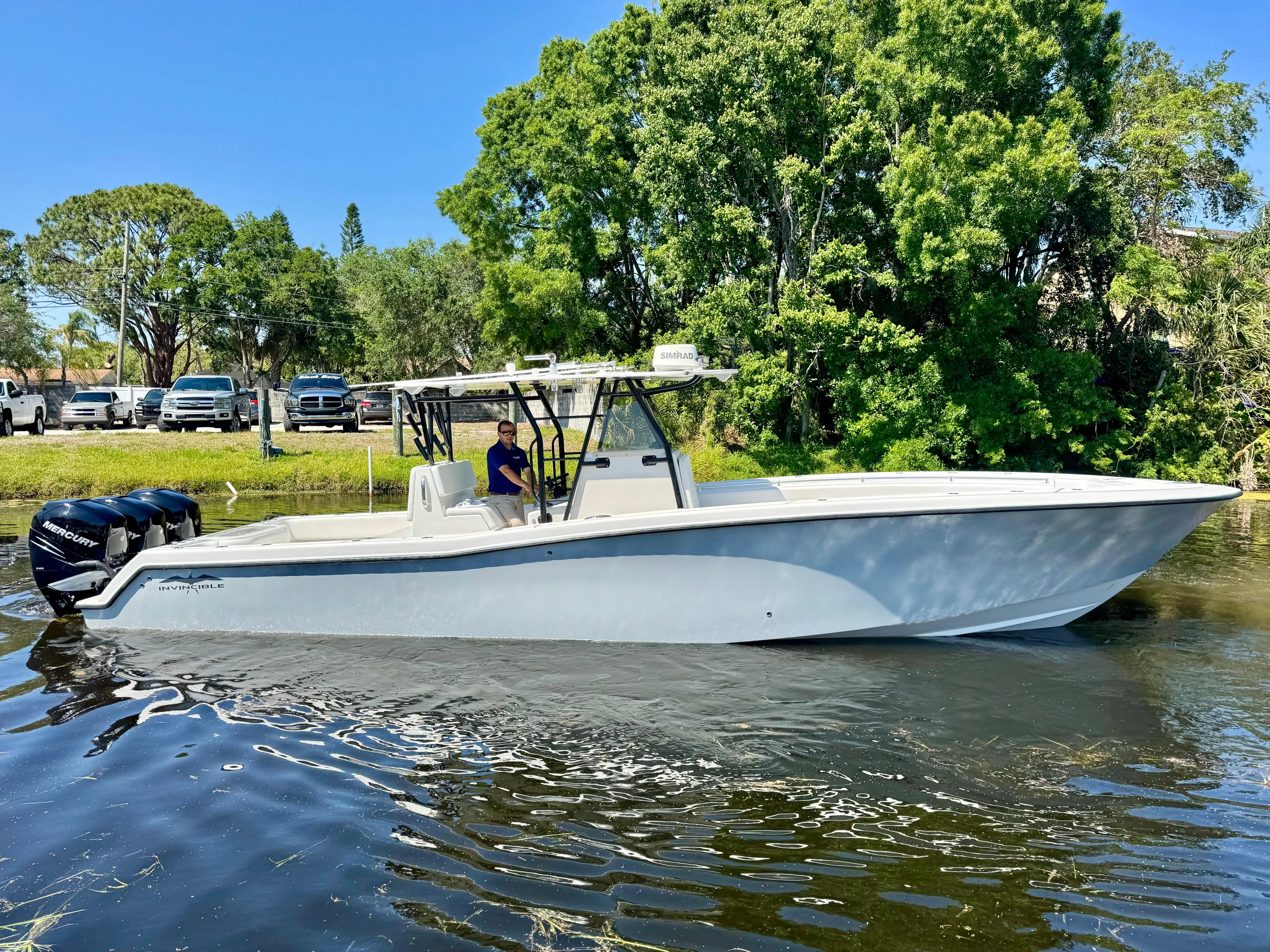  Yacht Photos Pics 2009 Invincible 36 Open Fisherman boat on calm water, surrounded by lush greenery.