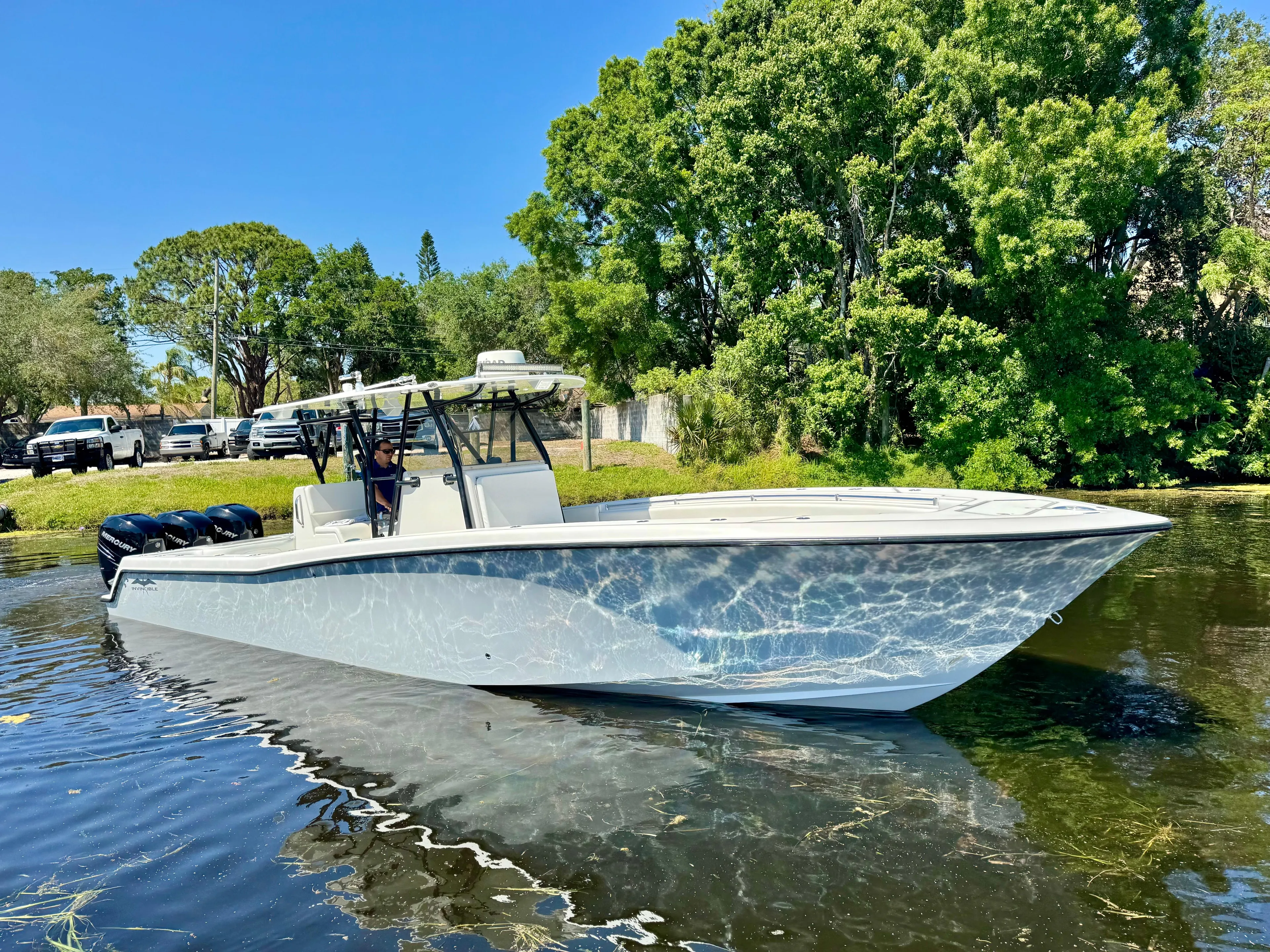  Yacht Photos Pics 2009 Invincible 36 Open Fisherman boat on calm water, surrounded by lush greenery.