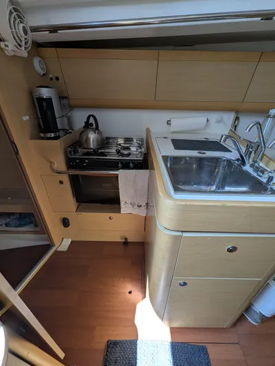 Saga Yacht Photos Pics Compact kitchen in a 2012 Beneteau First 40 sailboat with stove, sink, and wooden cabinetry.