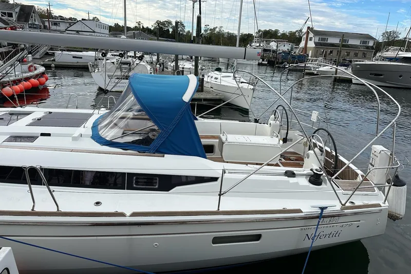  Yacht Photos Pics 2018 Jeanneau Sun Odyssey 479 sailboat docked in a marina, featuring a blue canopy.