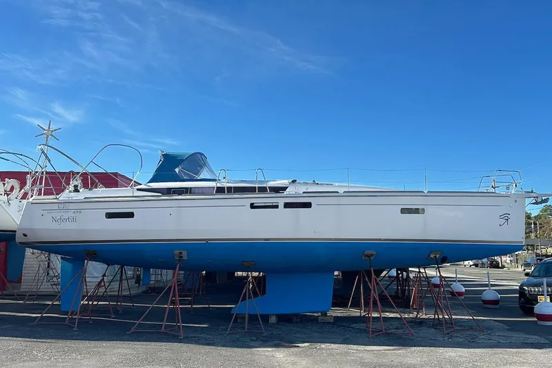  Yacht Photos Pics 2018 Jeanneau Sun Odyssey 479 sailboat on stands, blue hull, clear sky background.