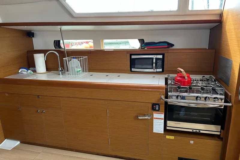  Yacht Photos Pics Modern kitchen in 2018 Jeanneau Sun Odyssey 479 yacht with stove, sink, and microwave.