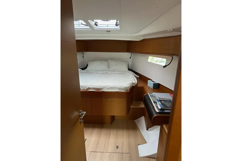  Yacht Photos Pics Cozy cabin interior of 2018 Jeanneau Sun Odyssey 479 sailboat with bed and wooden furnishings.