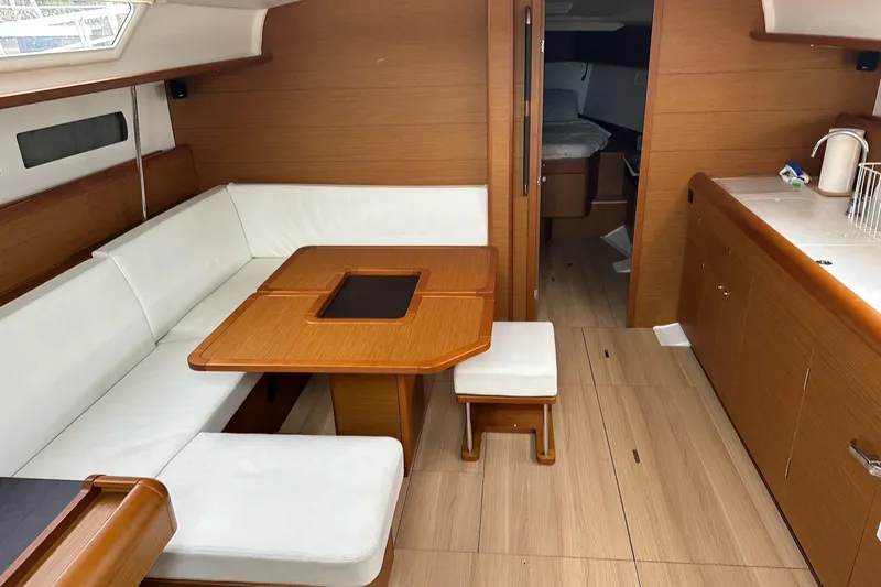  Yacht Photos Pics Interior of 2018 Jeanneau Sun Odyssey 479 yacht with wooden furnishings and white seating.