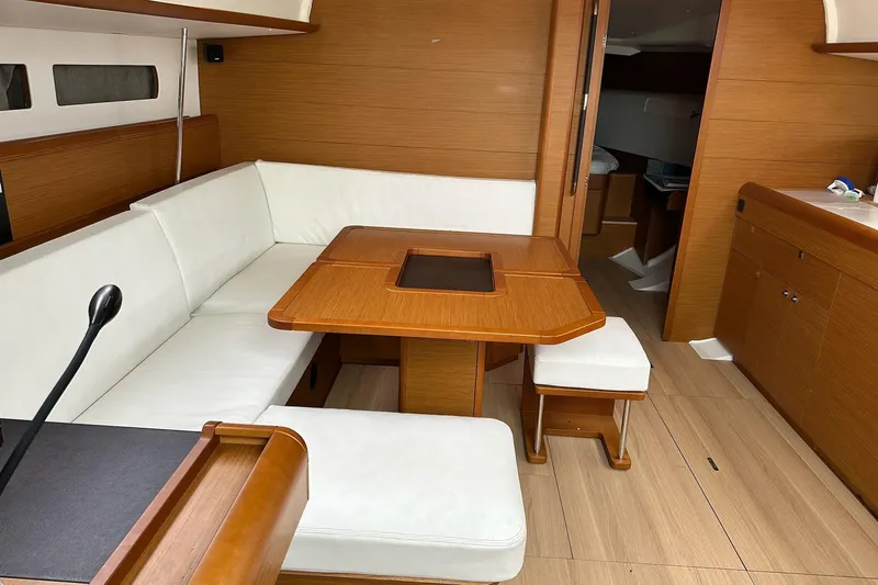  Yacht Photos Pics Interior of 2018 Jeanneau Sun Odyssey 479 yacht with wooden table and white seating.