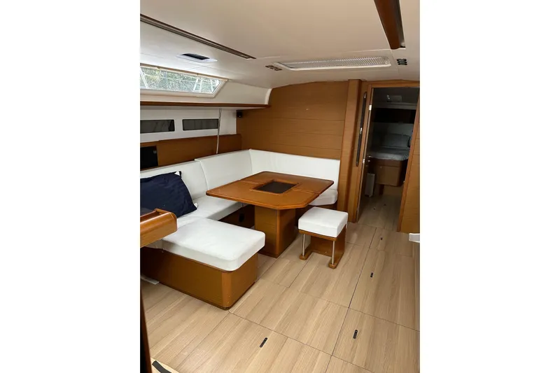  Yacht Photos Pics Interior of 2018 Jeanneau Sun Odyssey 479 yacht with wooden flooring and white seating.