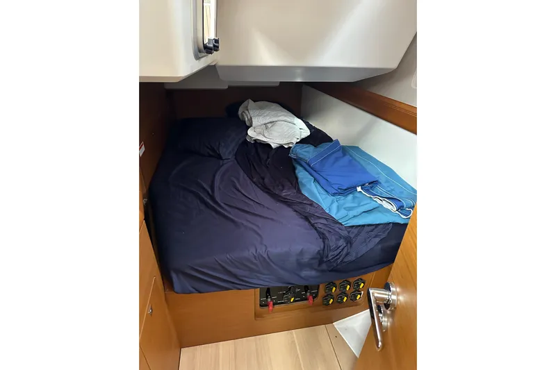  Yacht Photos Pics Cozy cabin bed in 2018 Jeanneau Sun Odyssey 479 sailboat, with navy bedding and folded clothes.