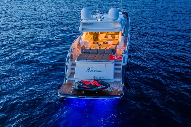 Gitana II Yacht Photos Pics Luxurious 2009 Princess V78 yacht with jet ski, illuminated on calm ocean waters.