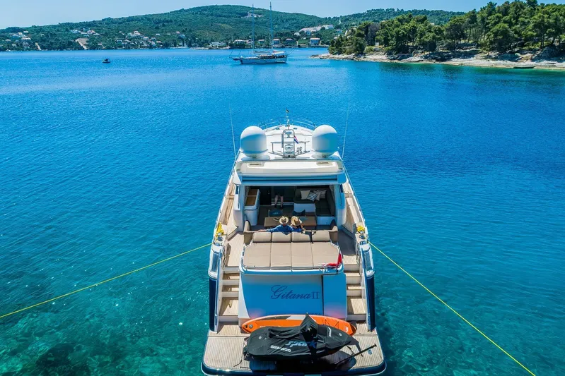 Gitana II Yacht Photos Pics Luxurious 2009 Princess V78 yacht anchored in clear blue waters, scenic coastal backdrop.