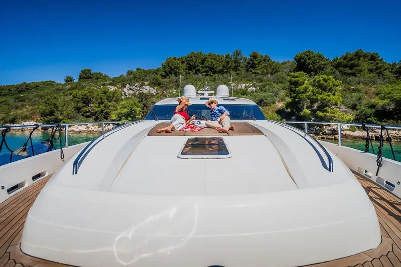 Gitana II Yacht Photos Pics Couple relaxing on 2009 Princess V78 yacht deck, surrounded by lush greenery and clear blue water.