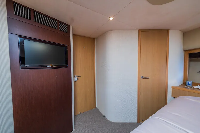 Gitana II Yacht Photos Pics Interior of 2009 Princess V78 yacht cabin with TV, wooden doors, and cozy bed.