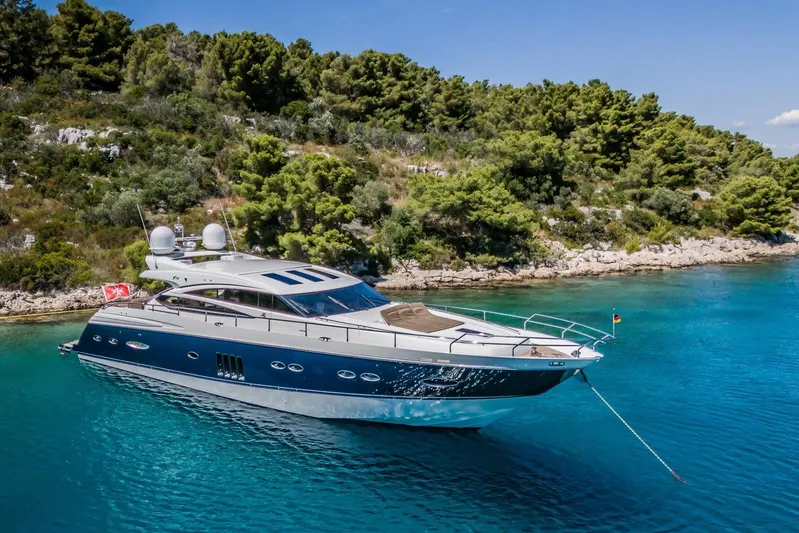 Gitana II Yacht Photos Pics Luxurious 2009 Princess V78 yacht anchored in clear blue waters near a lush, green coastline.