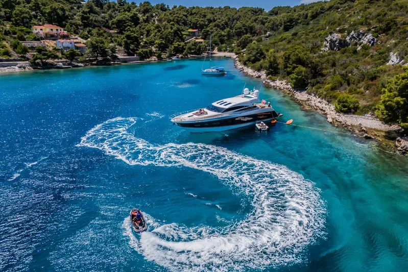 Gitana II Yacht Photos Pics Luxurious 2009 Princess V78 yacht anchored in a scenic, turquoise bay with jet ski nearby.