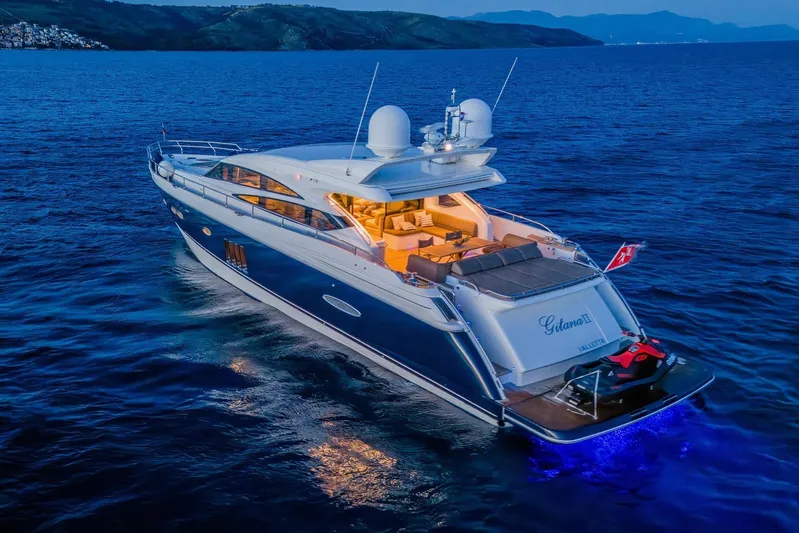 Gitana II Yacht Photos Pics Luxurious 2009 Princess V78 yacht illuminated on serene ocean waters at dusk.