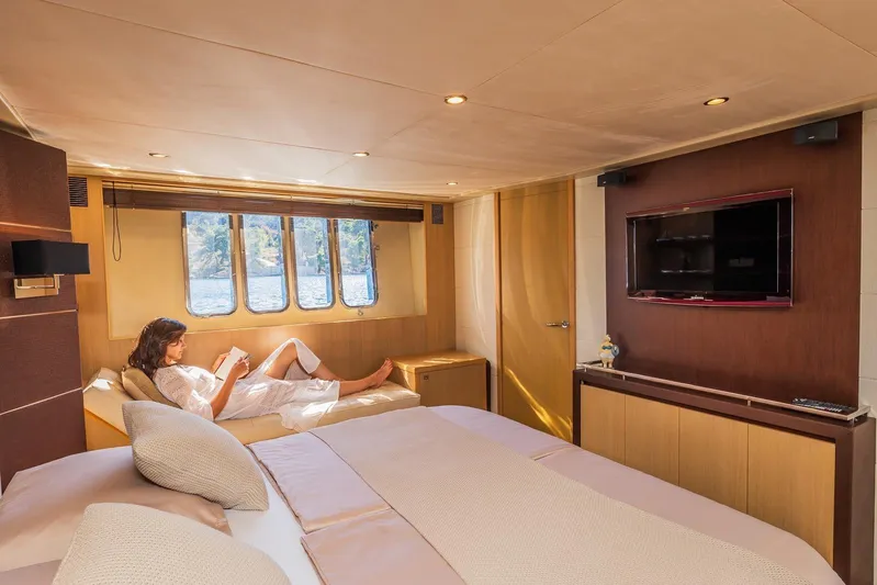 Gitana II Yacht Photos Pics Luxurious 2009 Princess V78 yacht bedroom with a person relaxing, large windows, and a TV.
