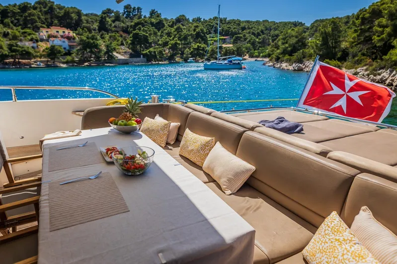 Gitana II Yacht Photos Pics Luxurious 2009 Princess V78 yacht deck with dining area, scenic coastal view, and vibrant flag.