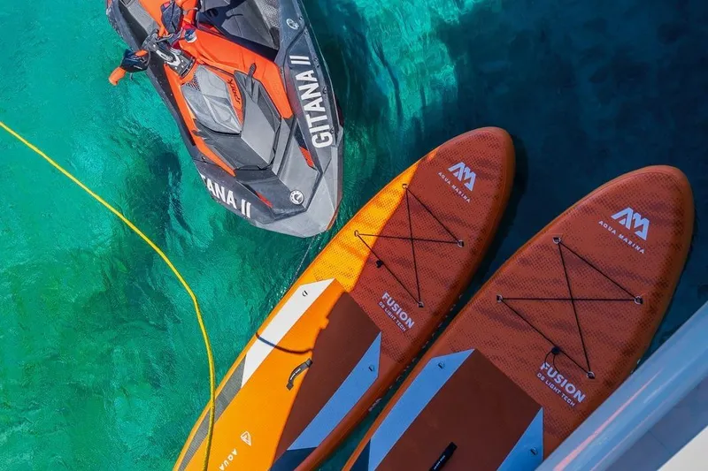 Gitana II Yacht Photos Pics Jet ski and paddleboards on clear turquoise water, near a 2009 Princess V78 yacht.