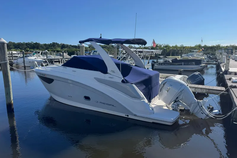  Yacht Photos Pics 2024 Regal 26 XO boat docked at marina, featuring sleek design and covered seating area.