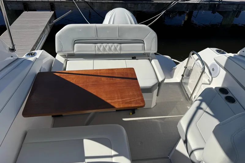  Yacht Photos Pics 2024 Regal 26 XO boat interior with seating and wooden table, dockside view.