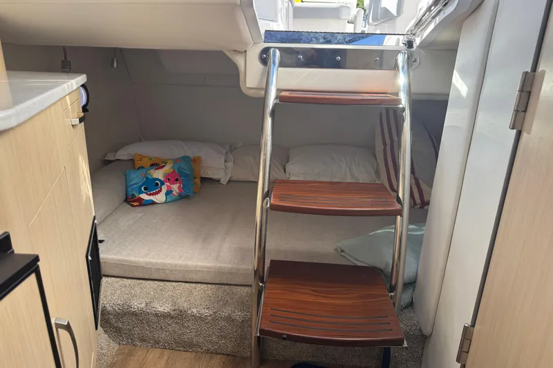  Yacht Photos Pics 2024 Regal 26 XO cabin interior with cozy bedding and wooden steps.