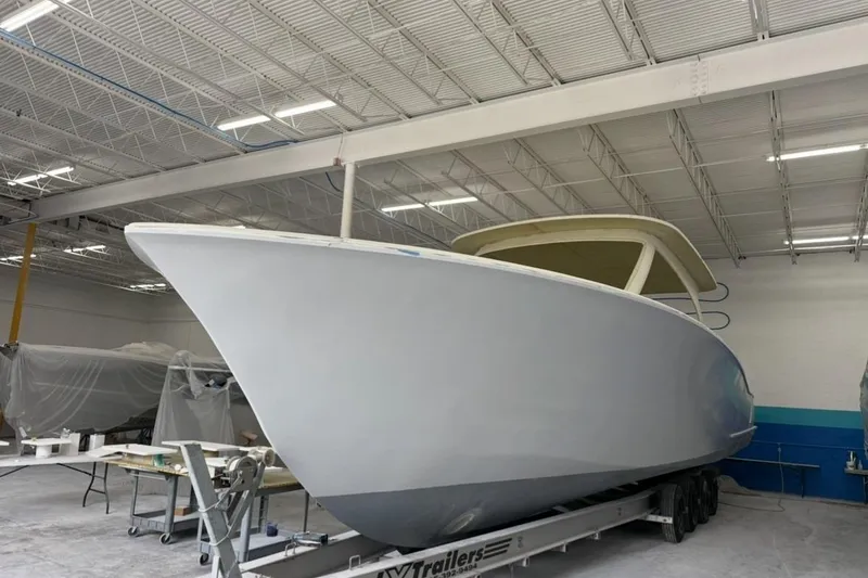 No Name Yacht Photos Pics 2025 Xcelerator Walk Around boat in a workshop on a trailer.