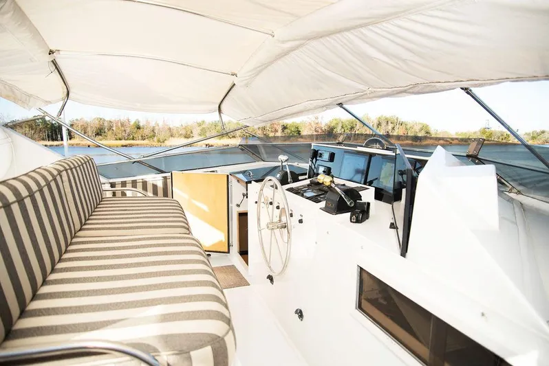 Happy Ours Yacht Photos Pics Luxurious 1989 Broward 85 Raised Pilothouse yacht interior with striped seating and helm.