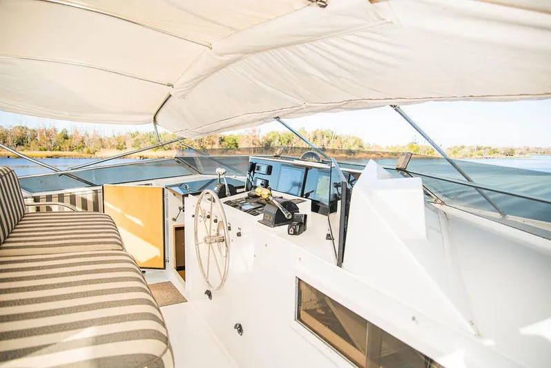 Happy Ours Yacht Photos Pics 1989 Broward 85 Raised Pilothouse yacht interior with striped seating and steering wheel.