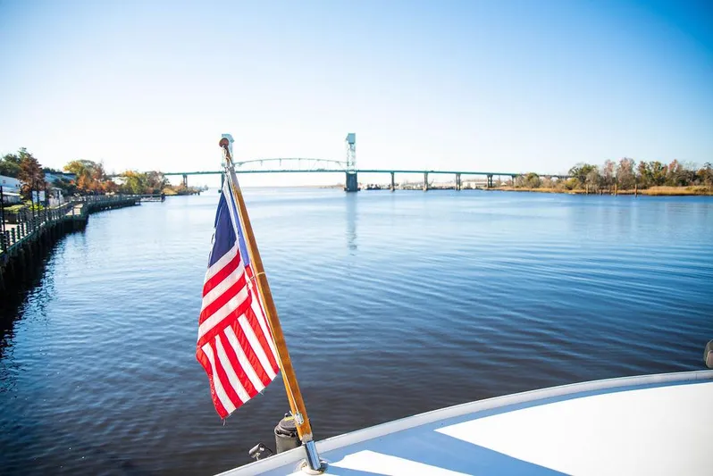 Happy Ours Yacht Photos Pics American flag on Broward 85 Raised Pilothouse yacht, 1989, with bridge and river view.