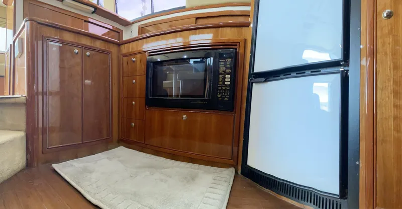 Warrior Yacht Photos Pics 2001 Riviera 43 Flybridge kitchen with microwave, fridge, and wooden cabinetry.