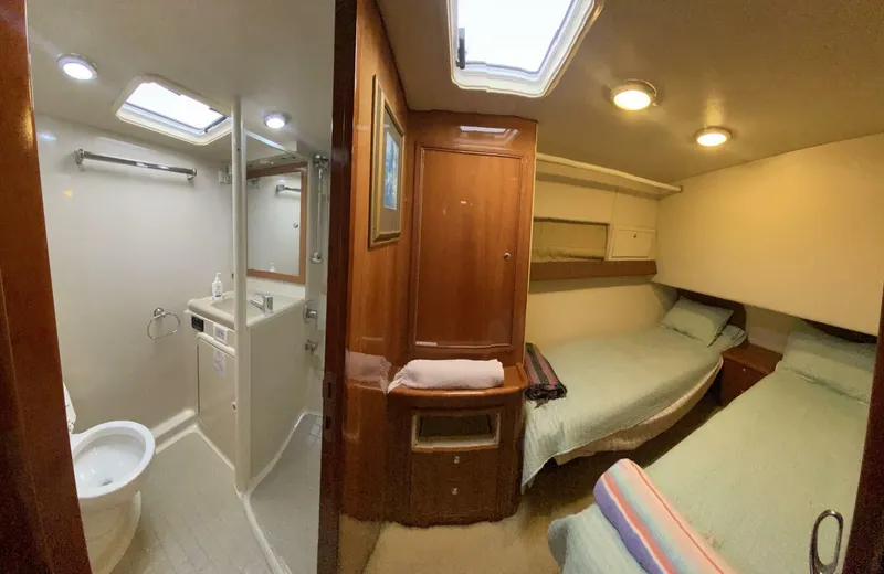 Warrior Yacht Photos Pics 2001 Riviera 43 Flybridge interior with twin beds and bathroom, featuring wood accents and skylights.