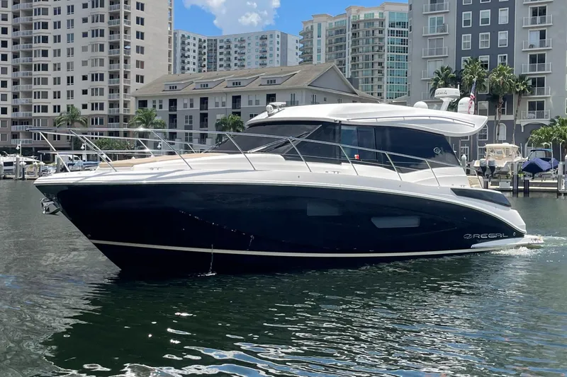 Caribbean Smile Yacht Photos Pics 2019 Regal 42 Grande Coupe yacht docked in a marina with high-rise buildings in the background.
