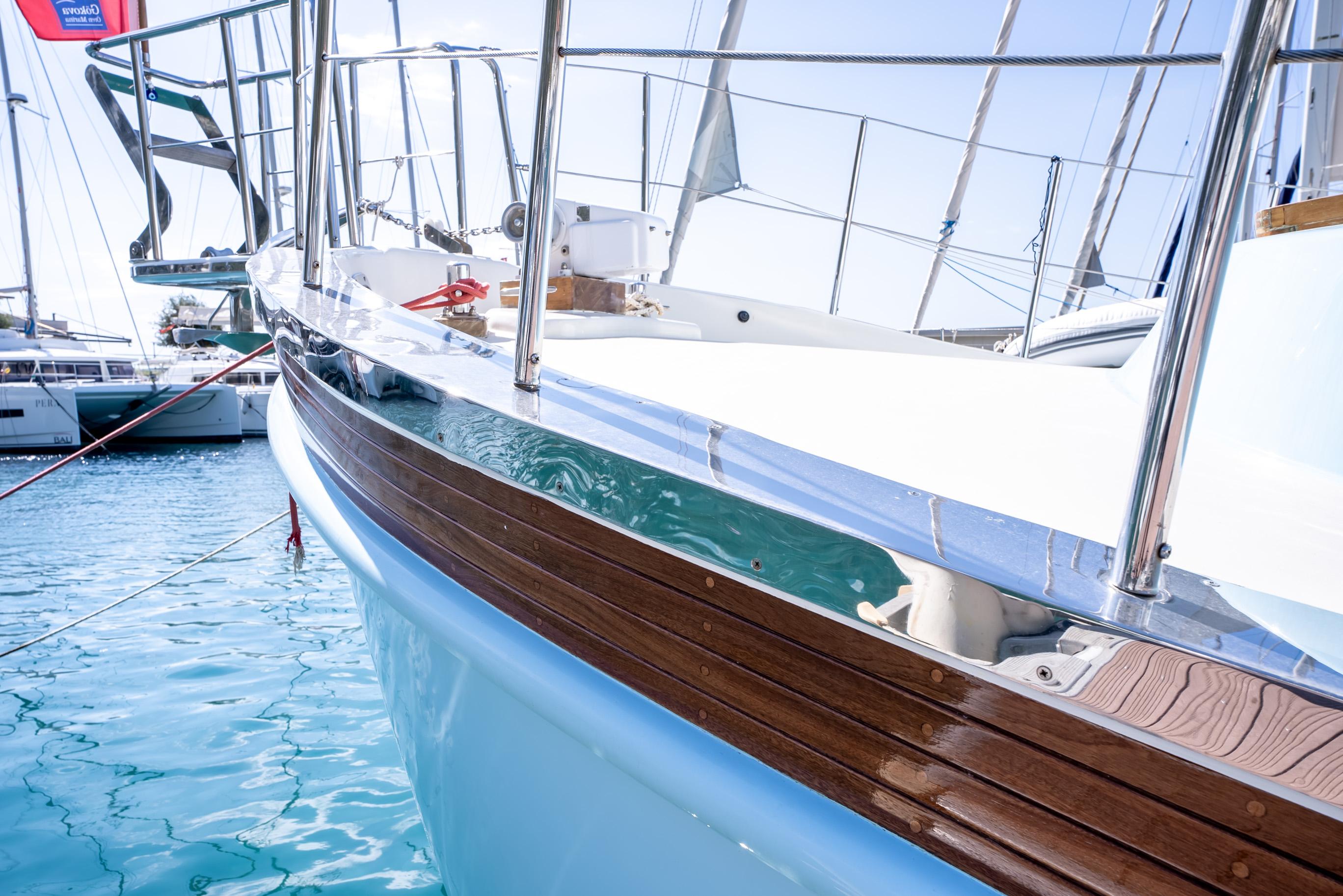 Custom 2016 trawler with wooden accents docked in a marina, reflecting on clear blue water.
