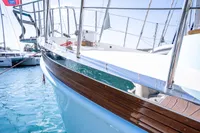Custom 2016 trawler with wooden accents docked in a marina, reflecting on clear blue water.