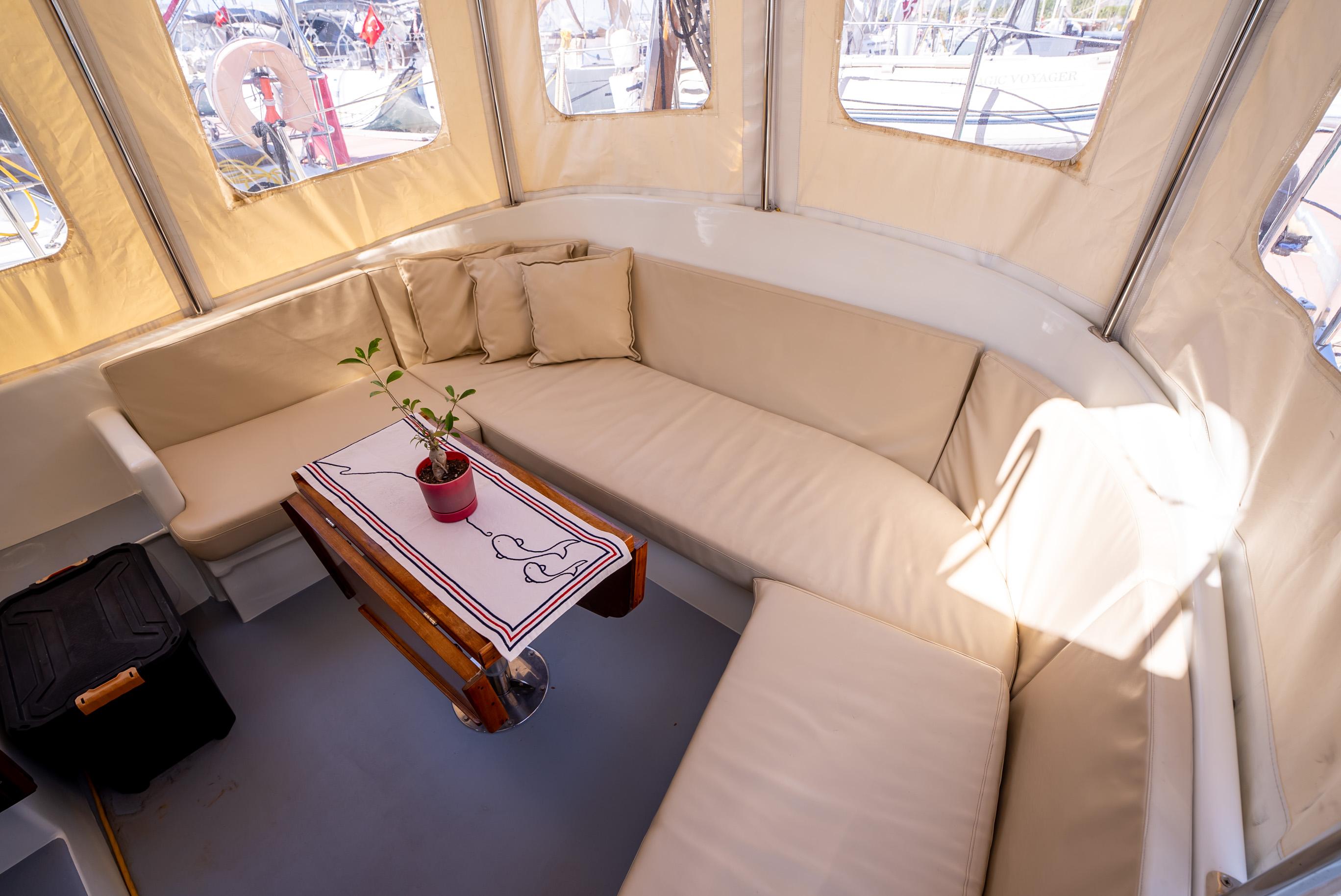Cozy seating area on a 2016 Custom Trawler with beige cushions and a small table.