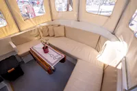 Cozy seating area on a 2016 Custom Trawler with beige cushions and a small table.