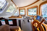 Interior of a 2016 custom trawler with wooden steering wheel and navigation equipment.