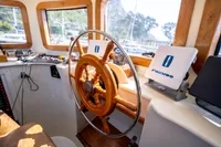 Helm of 2016 Custom Trawler with wooden wheel and navigation equipment.